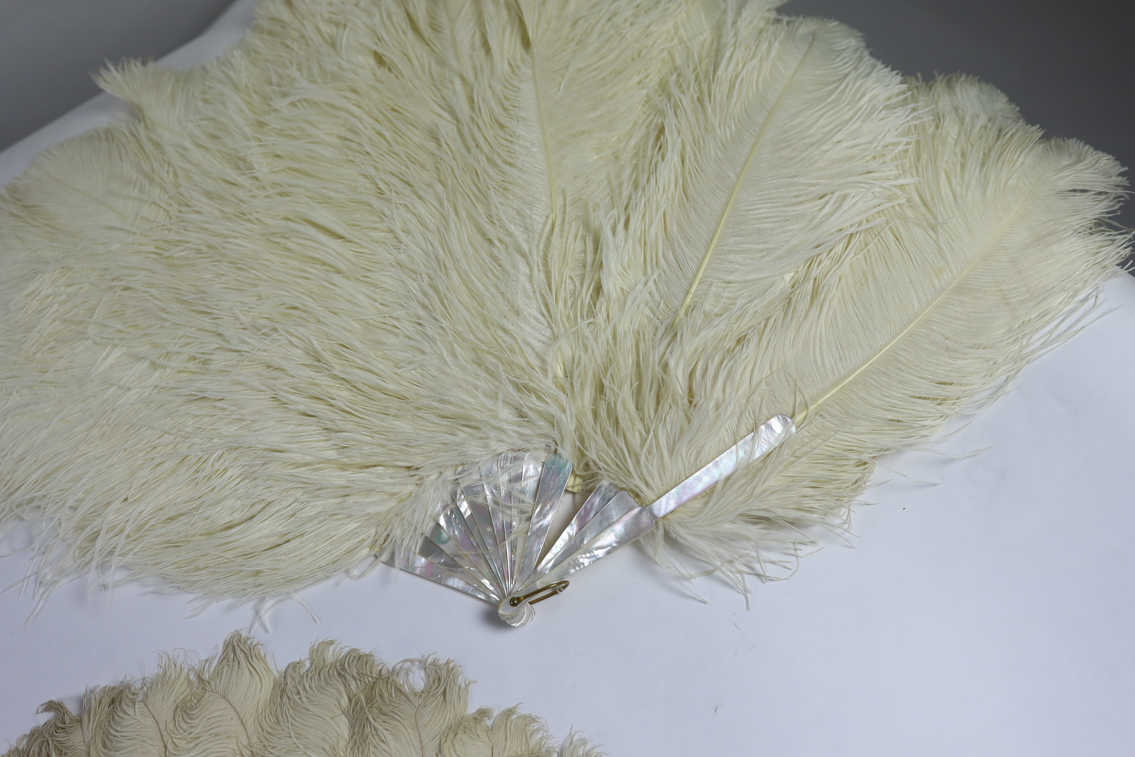 Two early 20th century Ostrich feather and mother of pearl fans, another similar fan with amber Bakelite handle and a small tortoiseshell and feather fan (4)